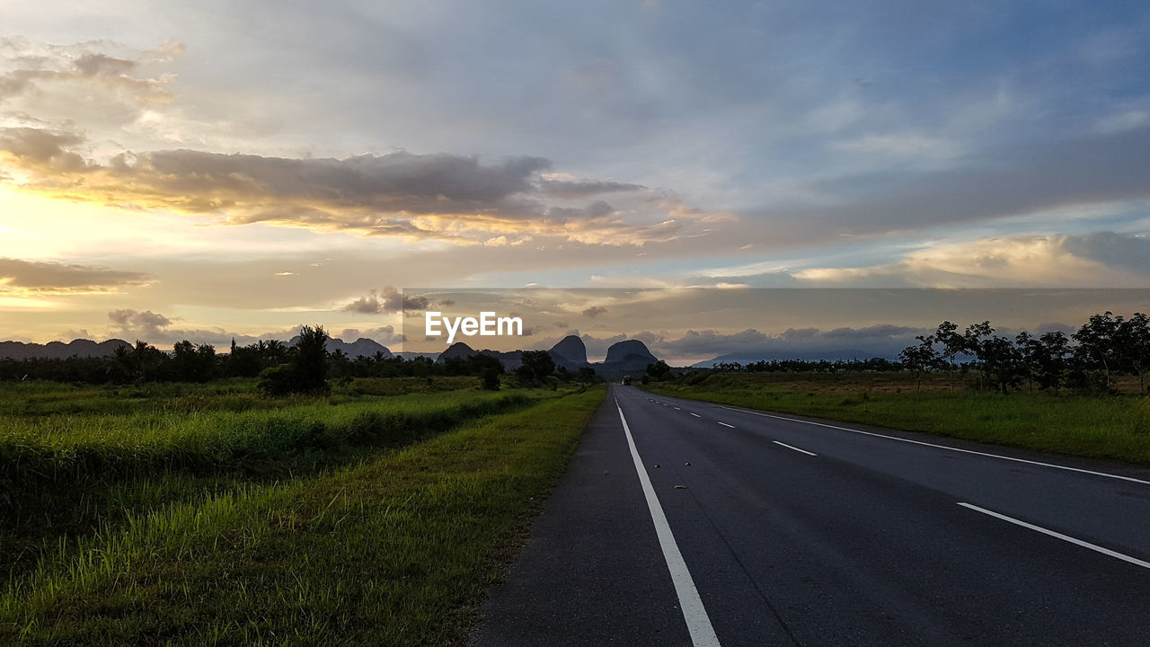 Road by landscape against sky during sunset