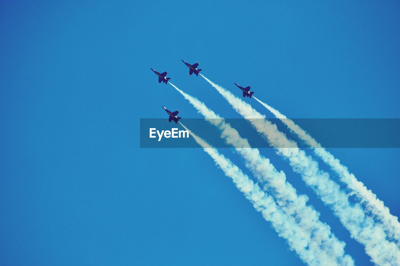 LOW ANGLE VIEW OF AIRSHOW AGAINST BLUE SKY