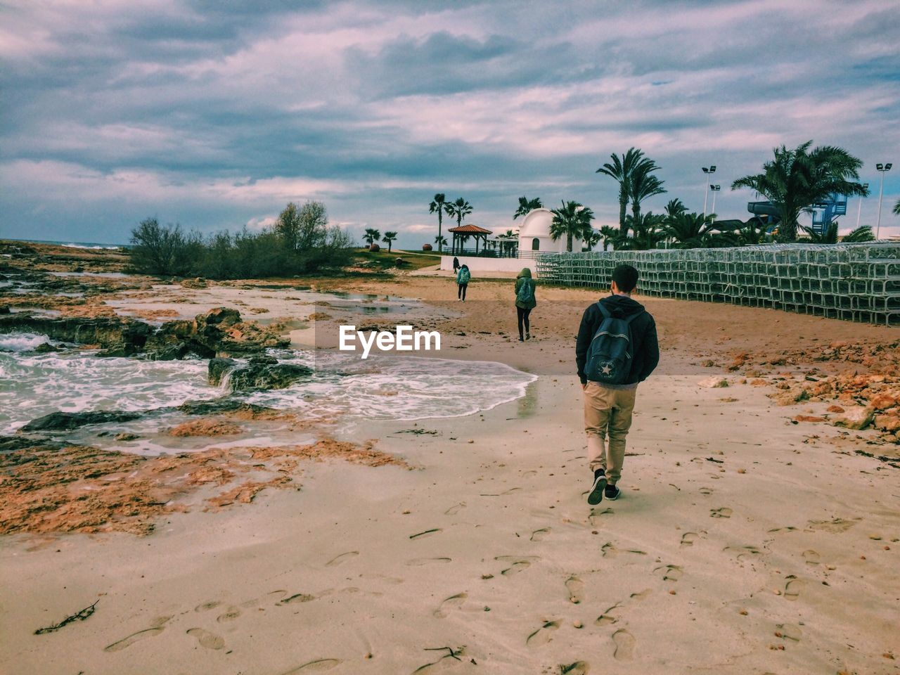 Man walking at beach against sky