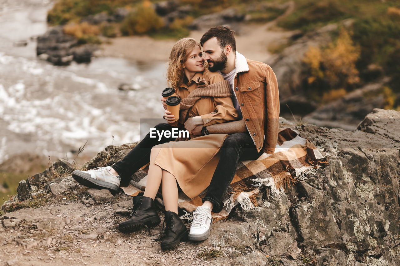 REAR VIEW OF COUPLE ON ROCK