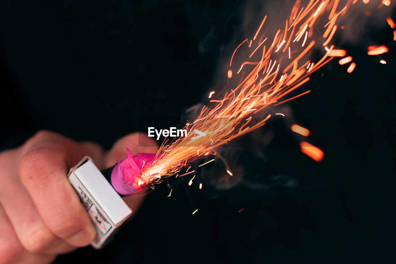 CLOSE-UP OF HAND HOLDING FIRE CRACKERS