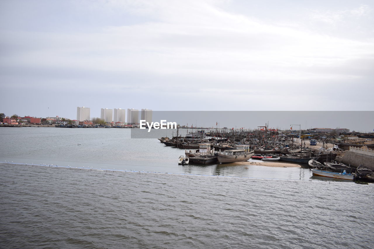 Nautical vessel on sea by buildings in city against sky