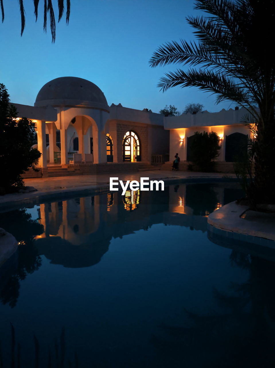 REFLECTION OF BUILDINGS IN SWIMMING POOL AT NIGHT