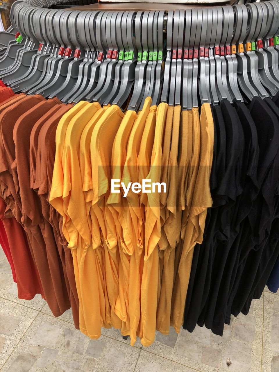 ROW OF MULTI COLORED CLOTHES HANGING ON RACK