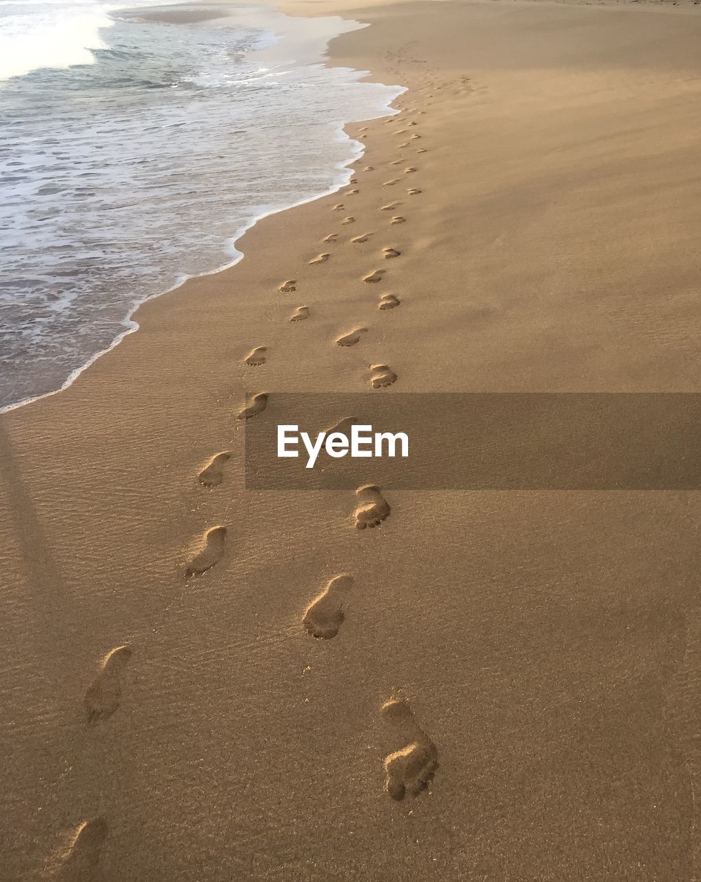 High angle view of footprints over sea shore at beach