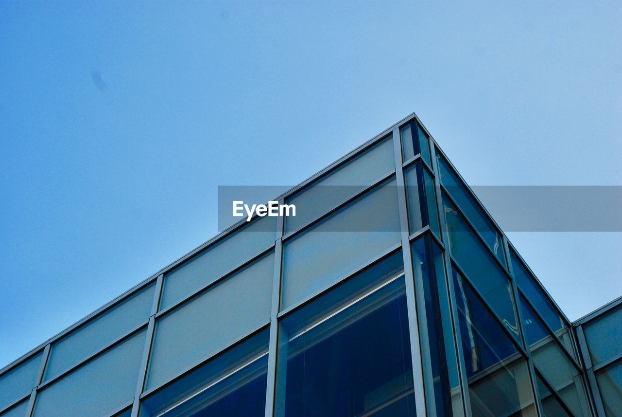 LOW ANGLE VIEW OF GLASS BUILDING AGAINST CLEAR BLUE SKY