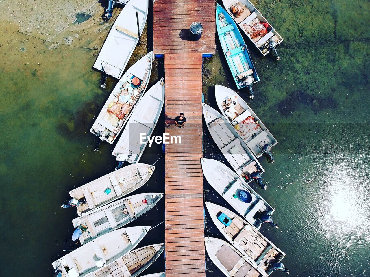 High angle view of man amidst sea on pier during sunny day