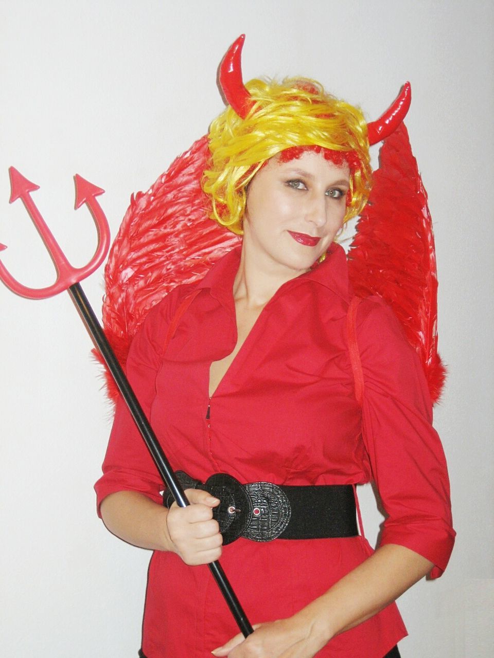 Portrait of smiling young woman in costume standing against wall