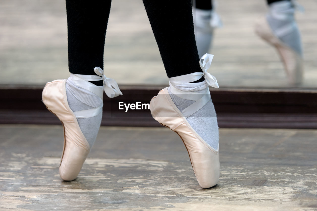 Low section of ballerina tiptoeing on hardwood floor