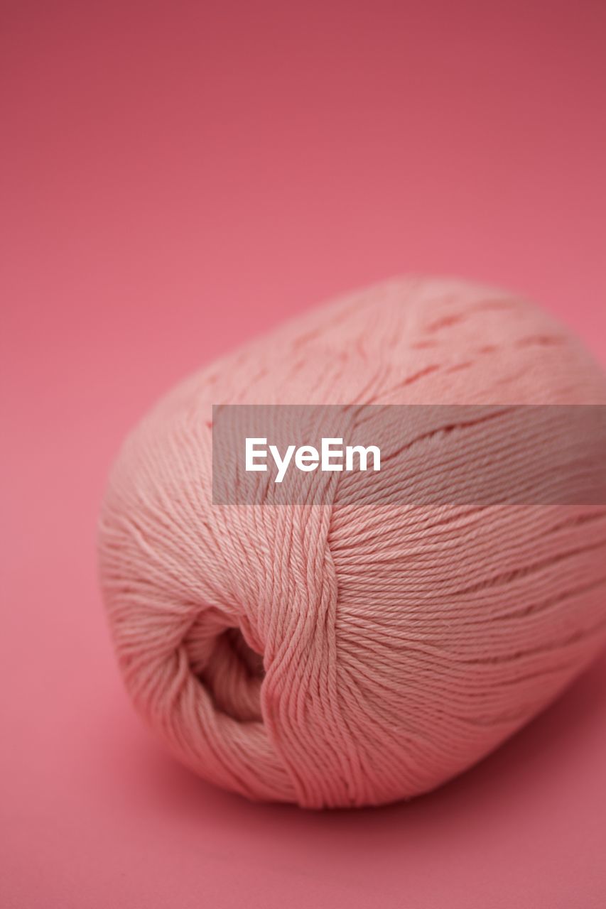 Close-up of spool over pink background