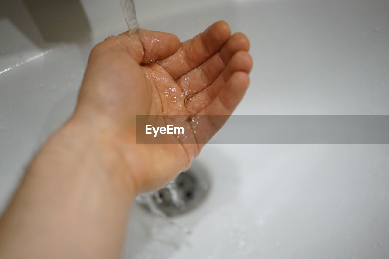 CLOSE-UP OF HAND TOUCHING WATER IN BATHTUB