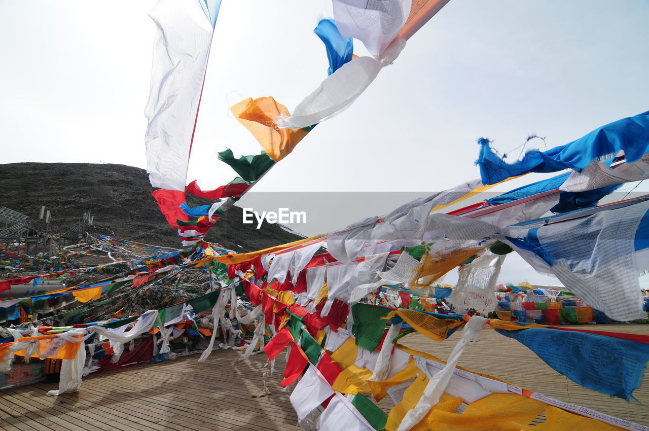 Prayer flags hanging over street on mountain against sky