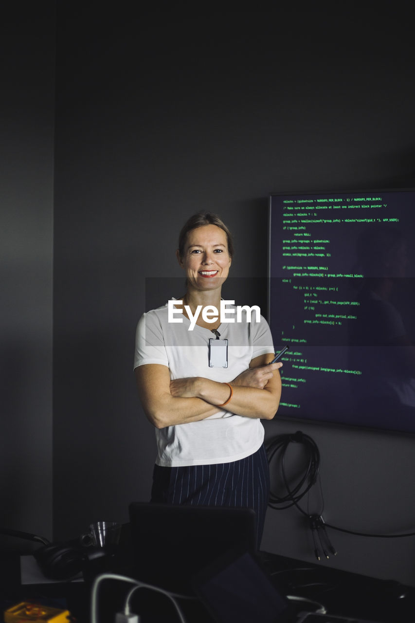 Portrait of smiling it professional working on projection screen in creative office