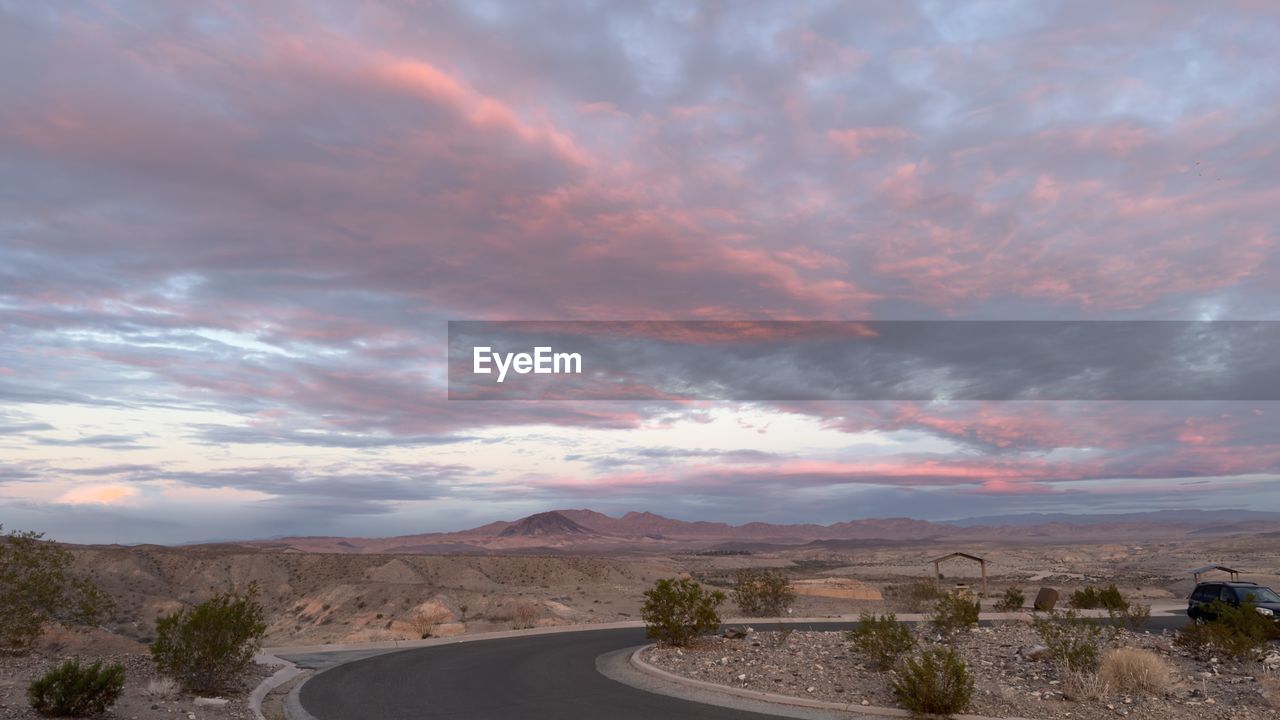 sky, cloud, road, landscape, environment, scenics - nature, nature, beauty in nature, horizon, transportation, mountain, sunset, plant, travel, no people, land, dramatic sky, travel destinations, dusk, outdoors, non-urban scene, tranquility, tree, curve, the way forward, tranquil scene, evening, cloudscape, highway, desert, remote, mountain range, road trip, tourism