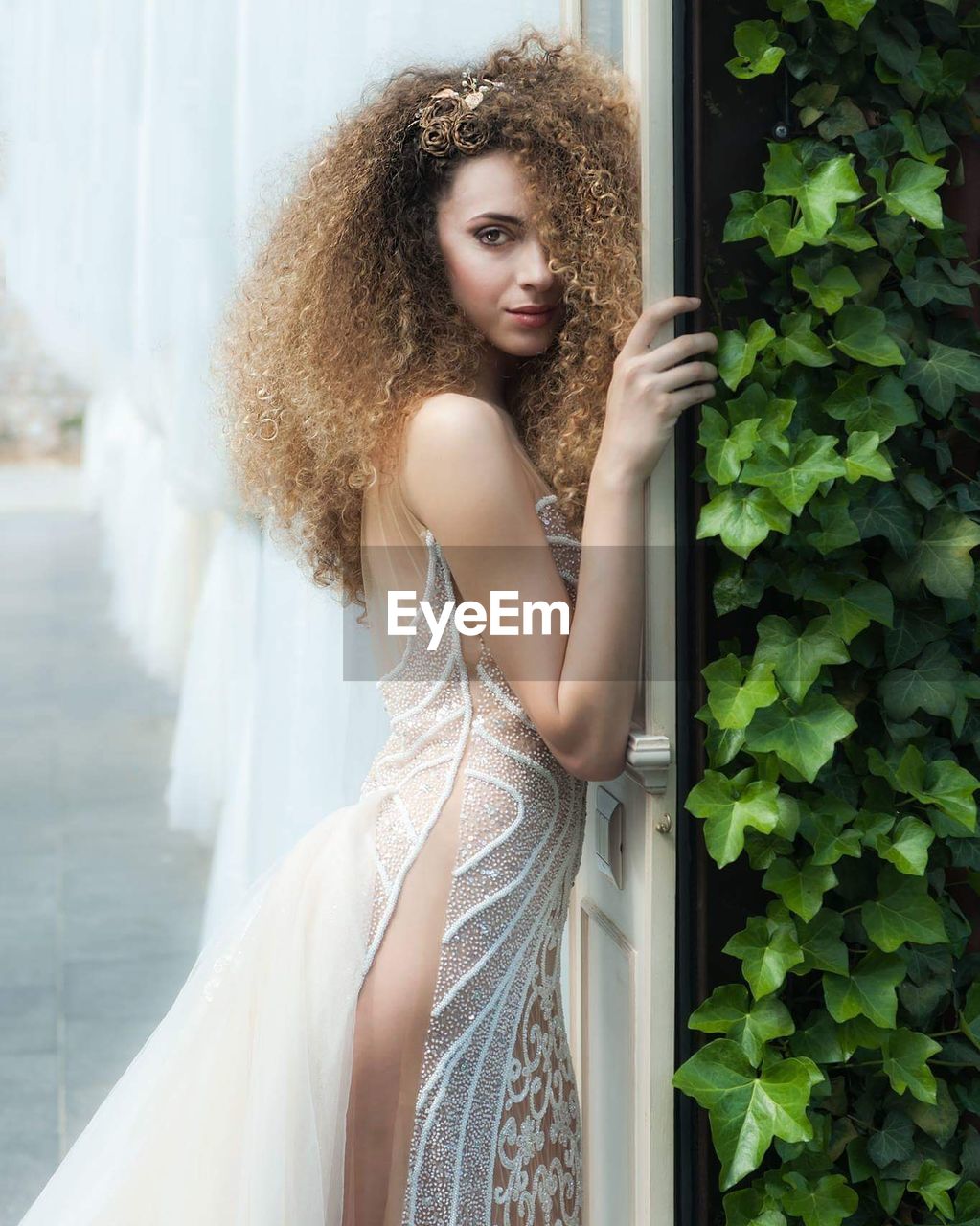 Side view portrait of fashionable young woman wearing white dress by plants