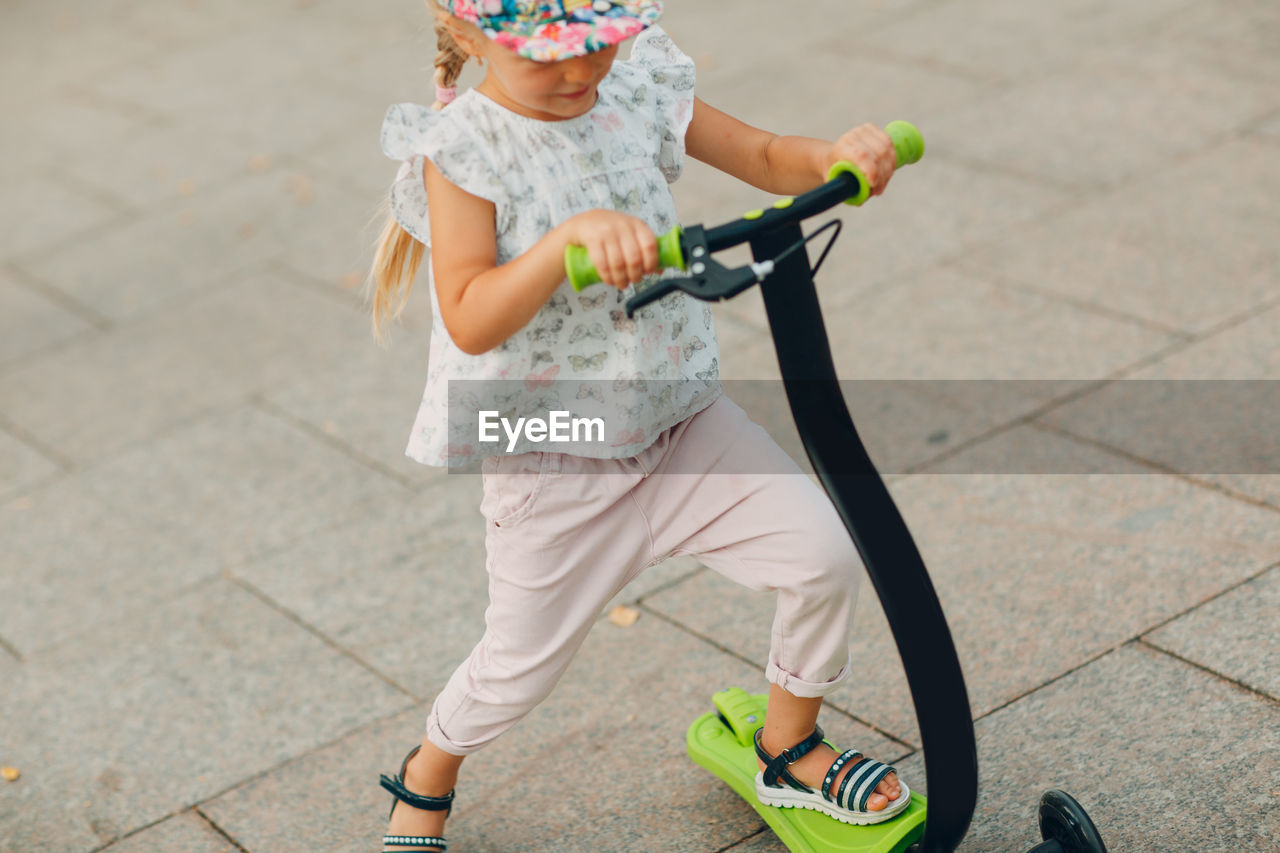 High angle view of girl riding push scooter on footpath