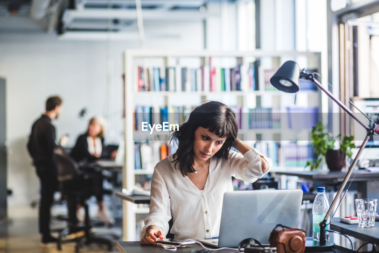 Businesswoman looking at laptop while sitting in office