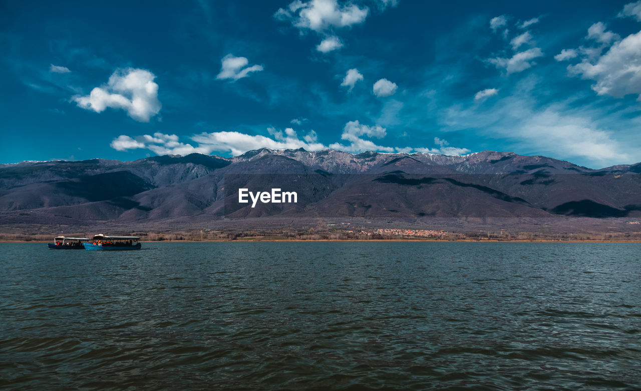 Scenic view of sea and mountains against sky