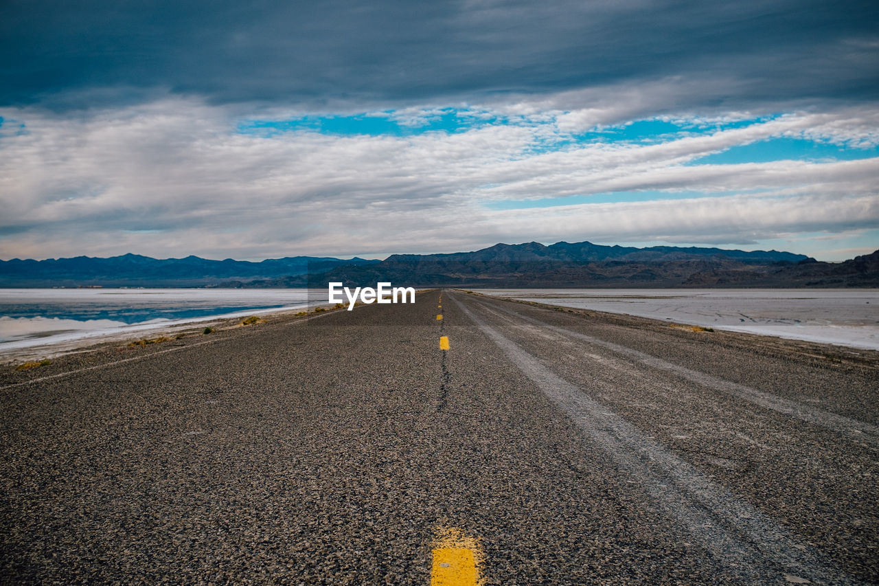 Road by mountains against sky