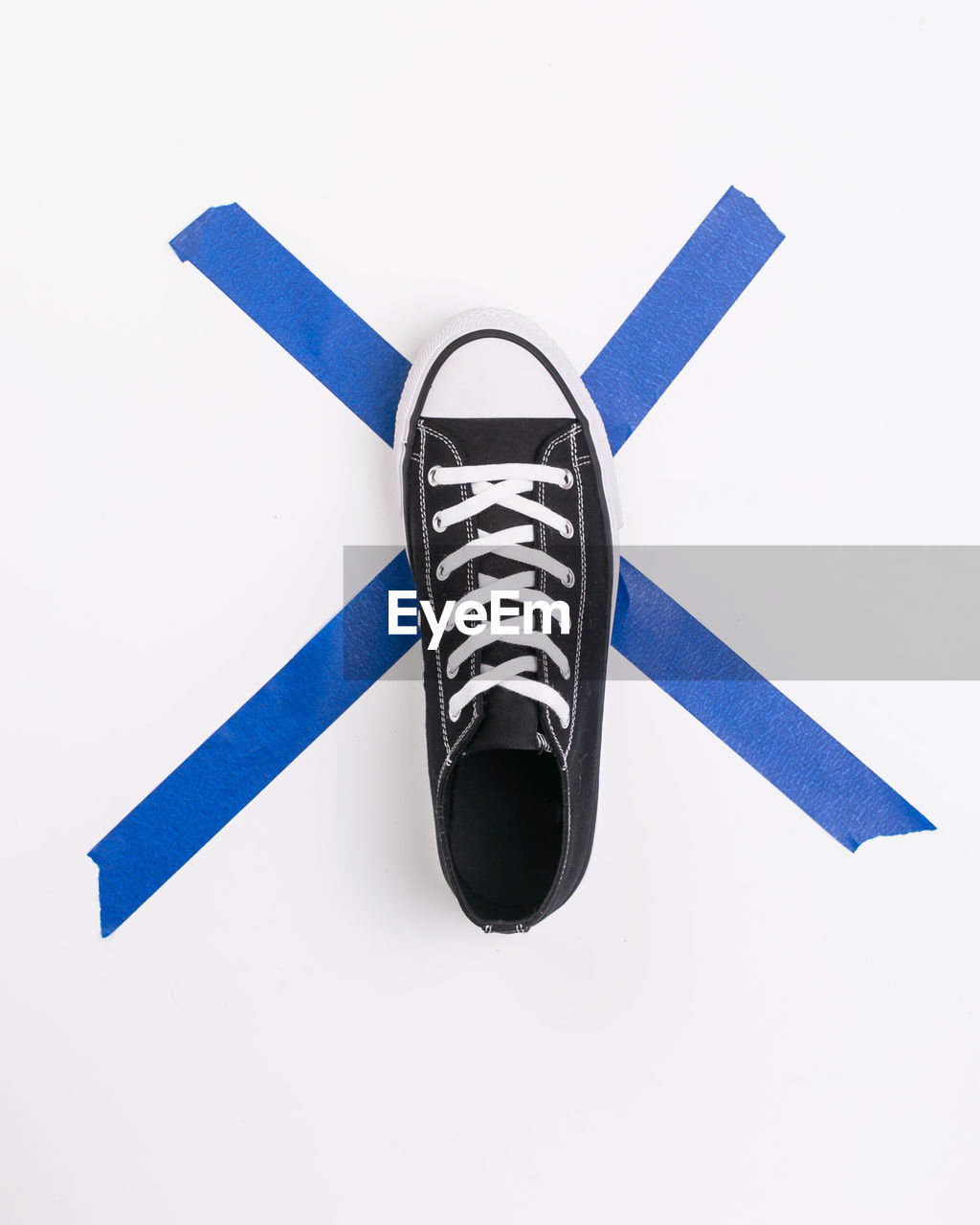 Directly above shot of canvas shoe and adhesive tape on white background