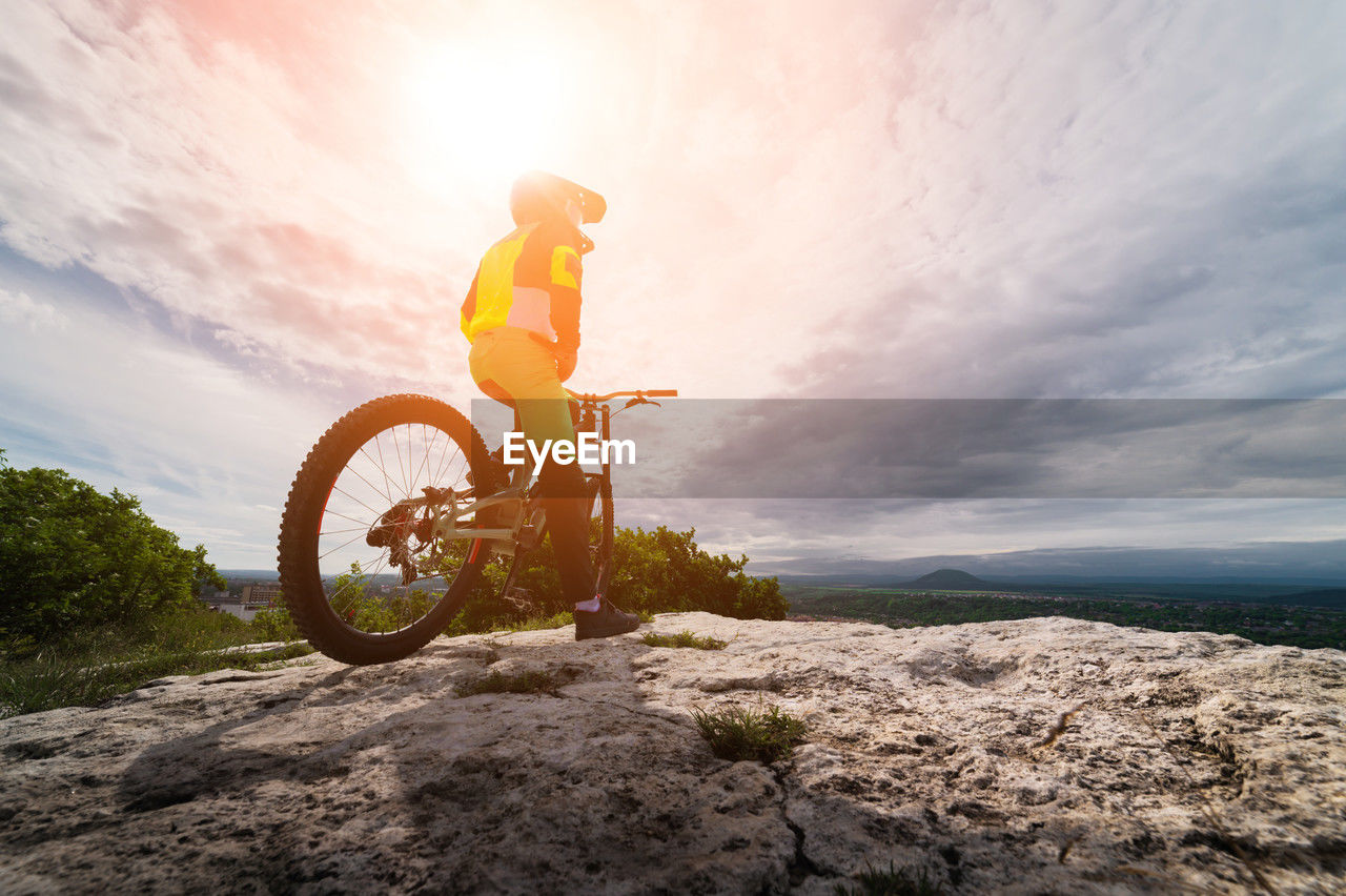 Guy sits on a mountain bike in a mountainous area against the backdrop of a private sector person