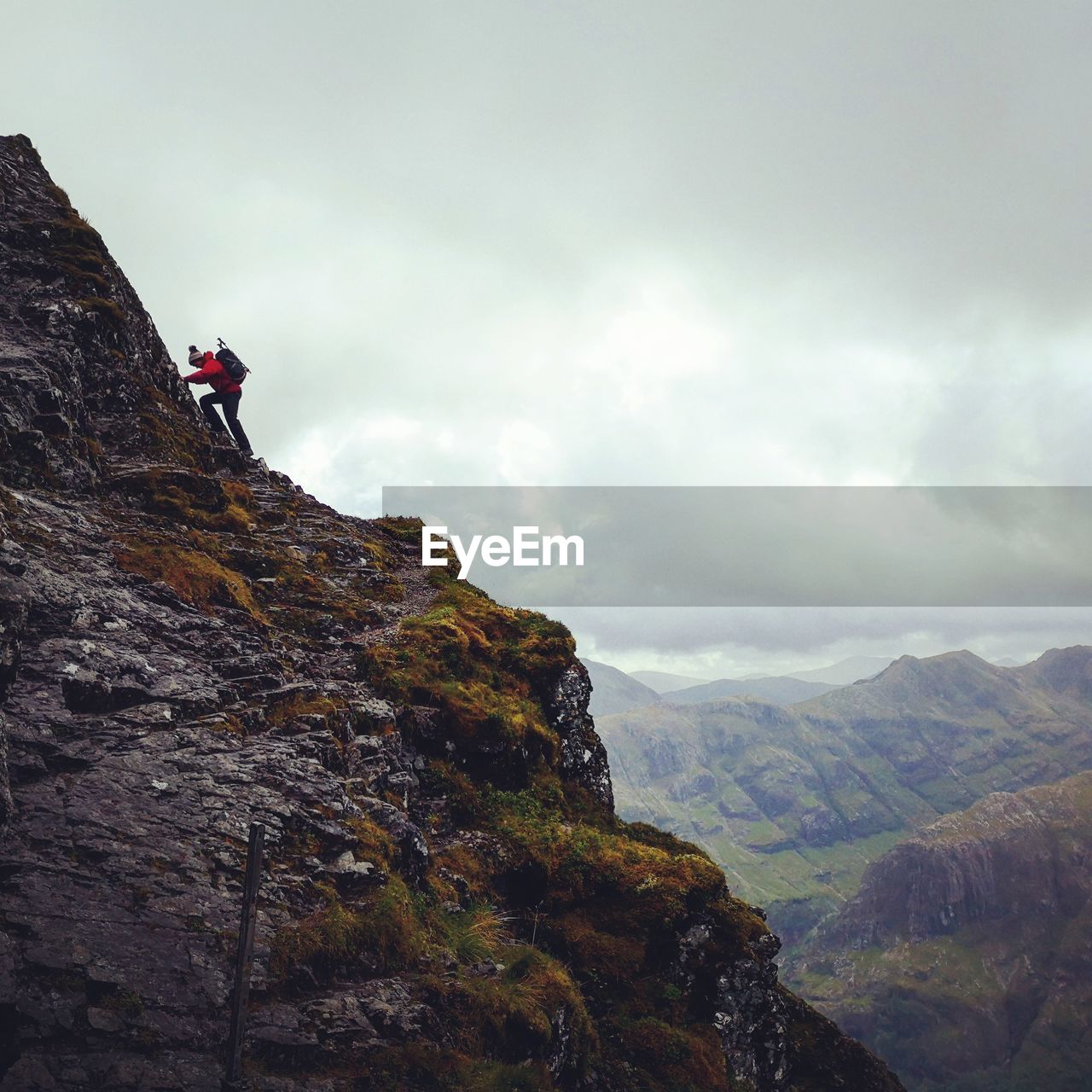 Low angle view of hiker climbing on mountain against sky