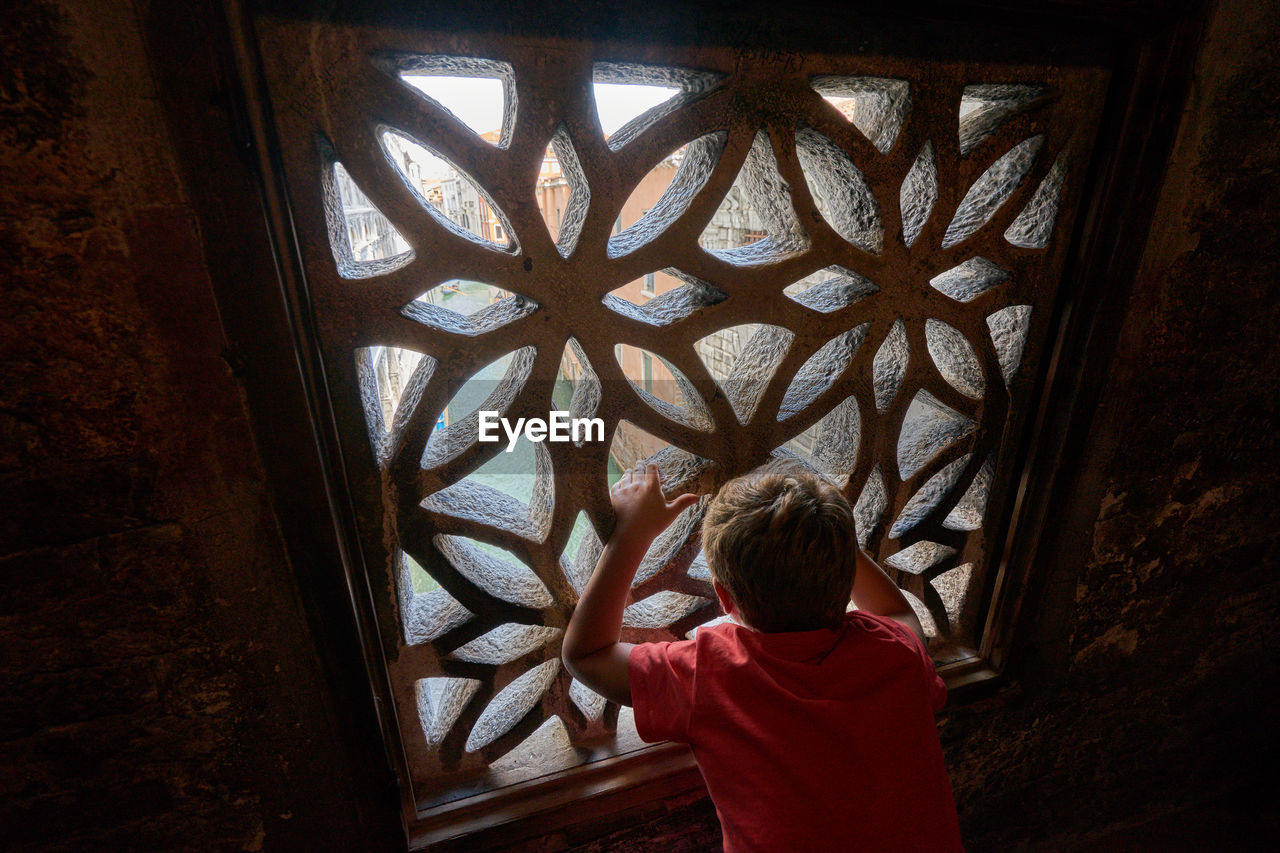 Rear view of boy standing by window in venice 