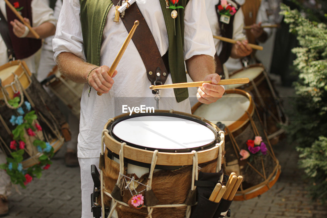 Midsection of people playing drum on street