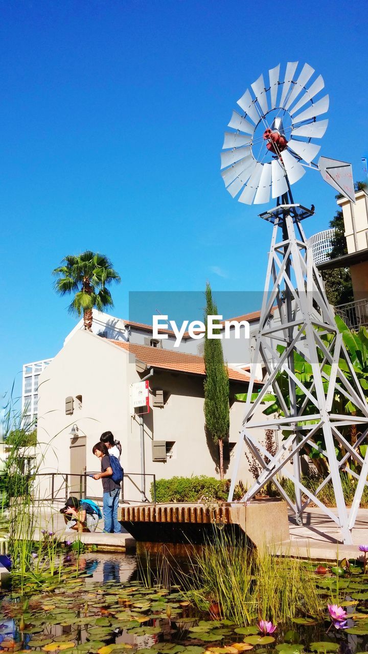 PEOPLE IN TRADITIONAL WINDMILL AGAINST SKY