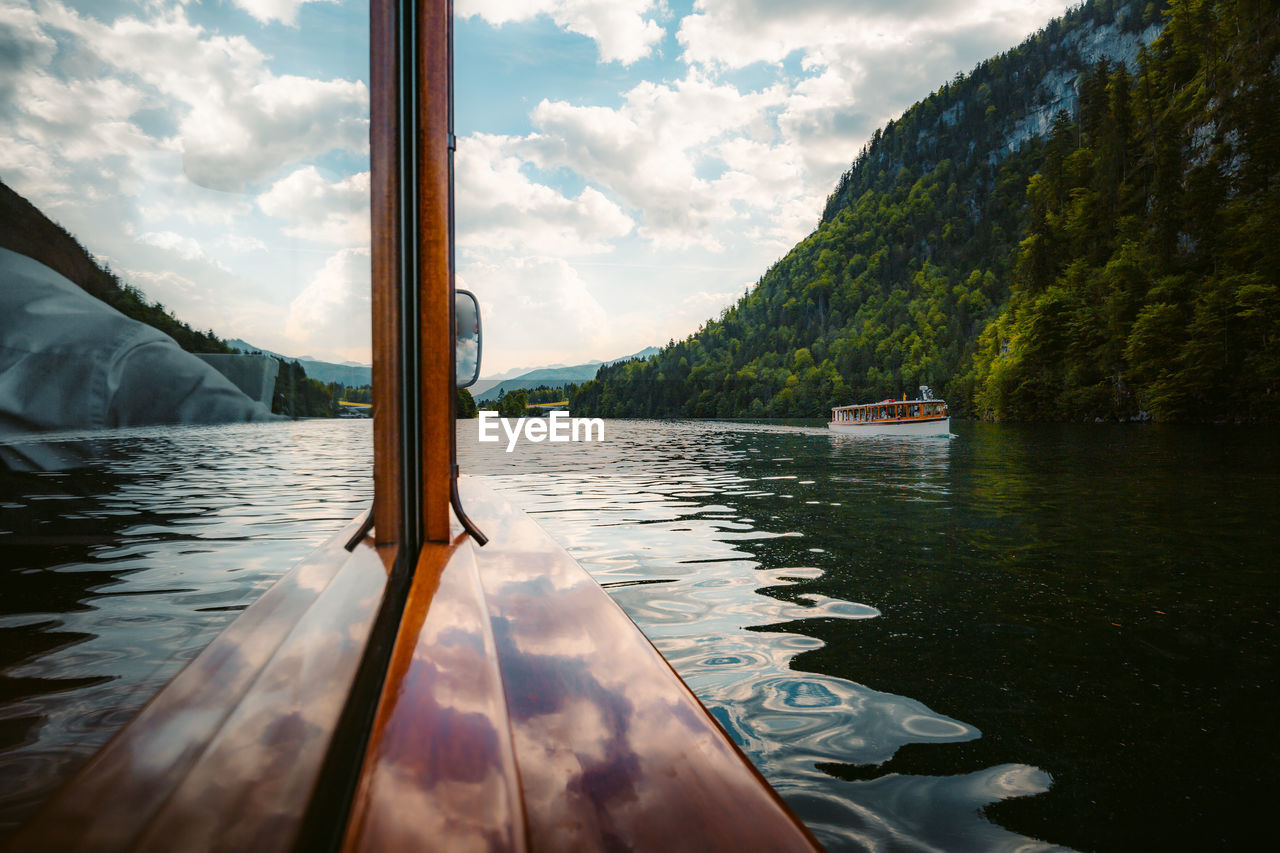 Boat moving in lake against cloudy sky