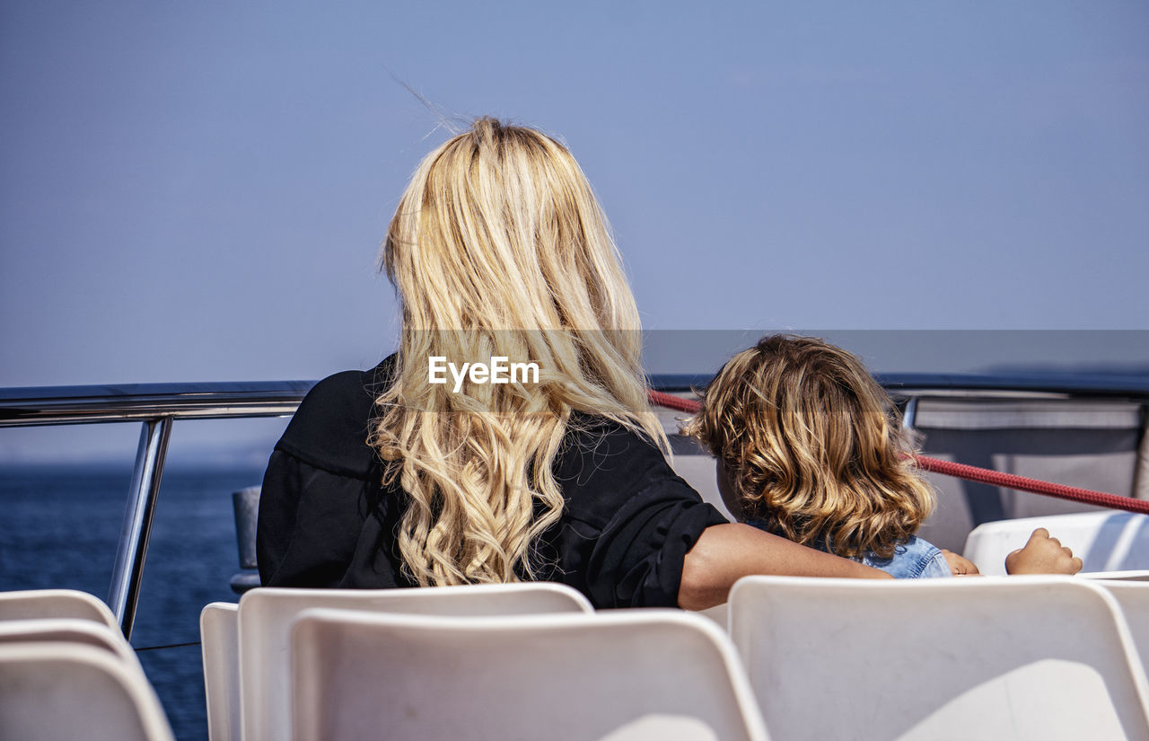 women, rear view, blond hair, transportation, adult, two people, mode of transportation, togetherness, travel, sitting, vehicle, ship, female, vacation, trip, sky, young adult, leisure activity, holiday, men, nature, sea, water, day, journey, lifestyles, hairstyle, copy space, child, nautical vessel, friendship, casual clothing, emotion, seat, long hair, bonding, relaxation, blue, outdoors, boat, summer, person, headshot, childhood, clear sky, sunny, clothing