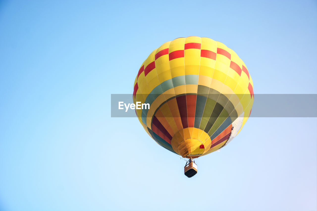 Low angle view of yellow hot air balloon flying against clear sky