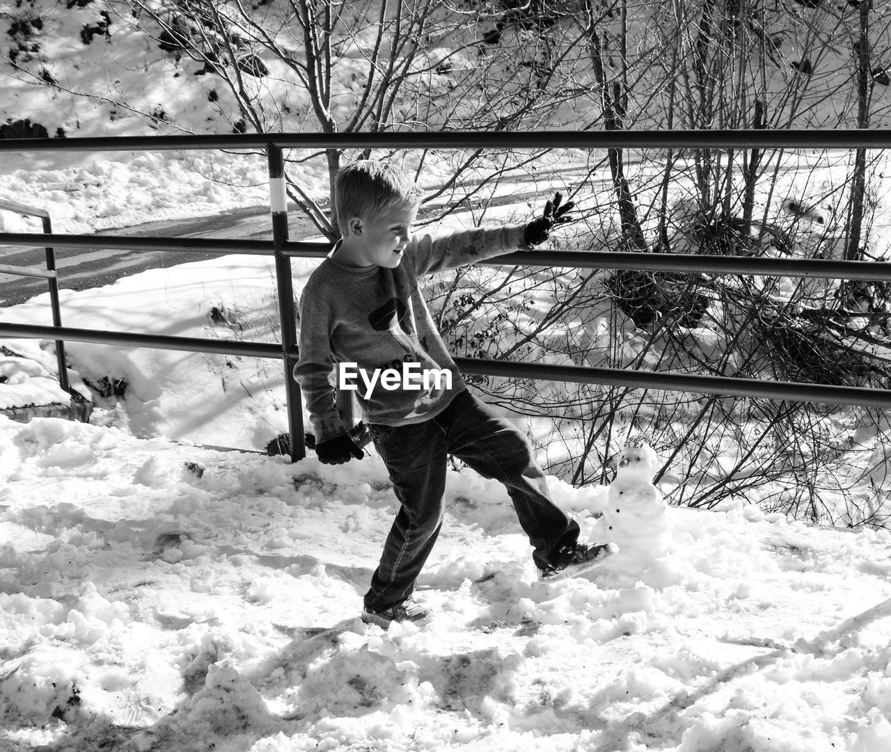 Boy making snowman in forest