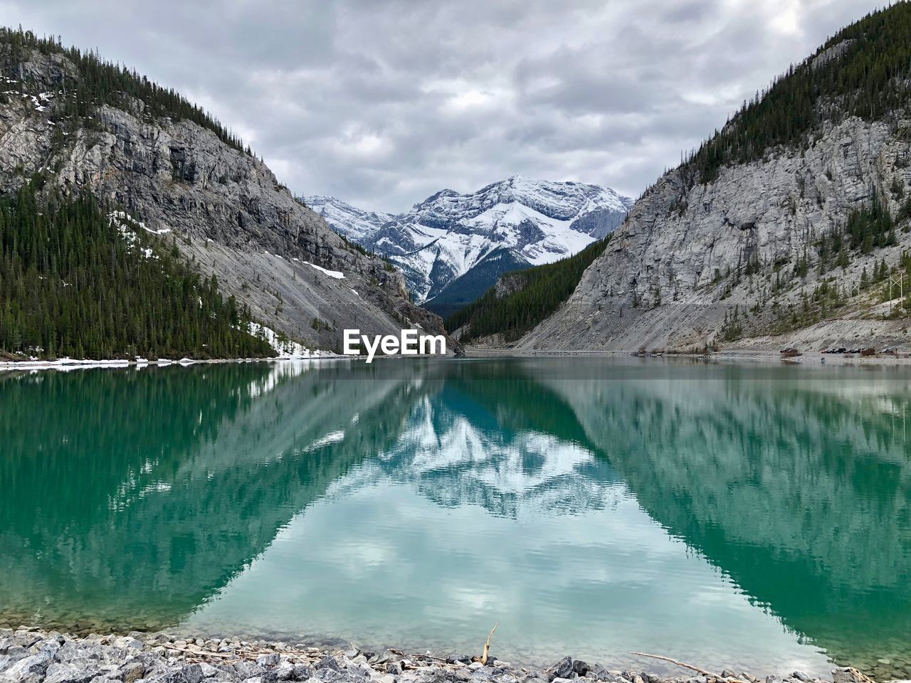 Scenic view of lake by snowcapped mountains against sky