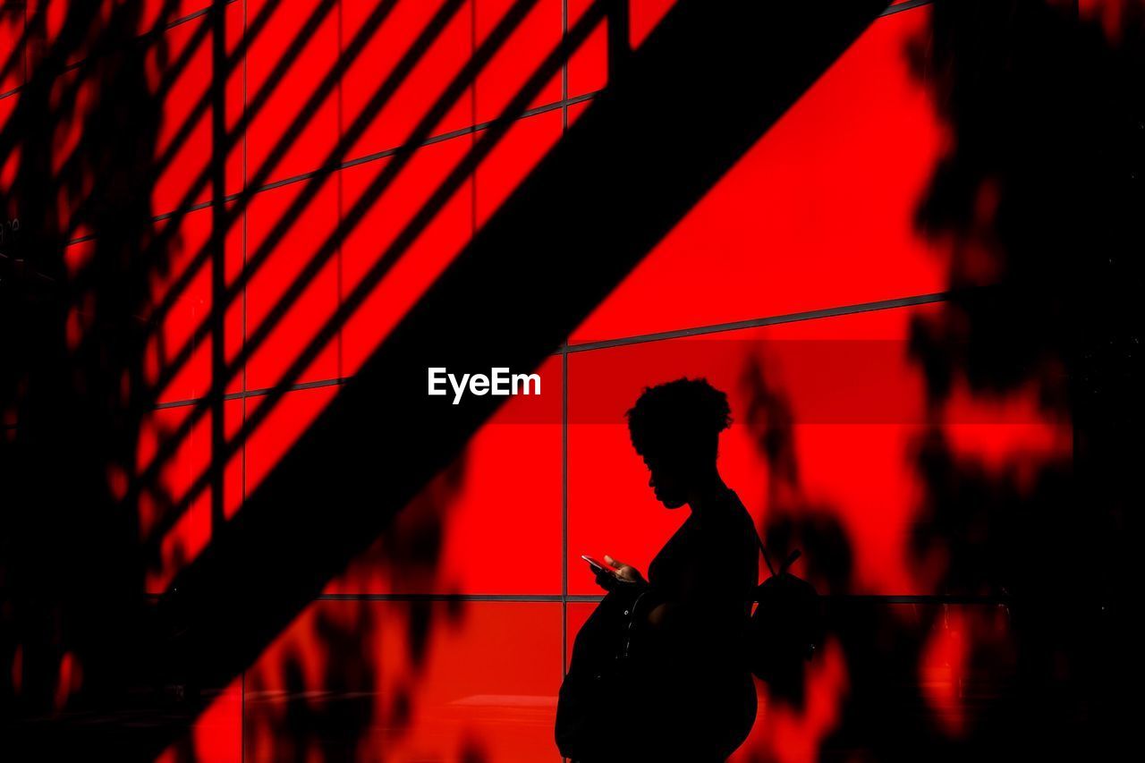 Silhouette of woman standing by wall