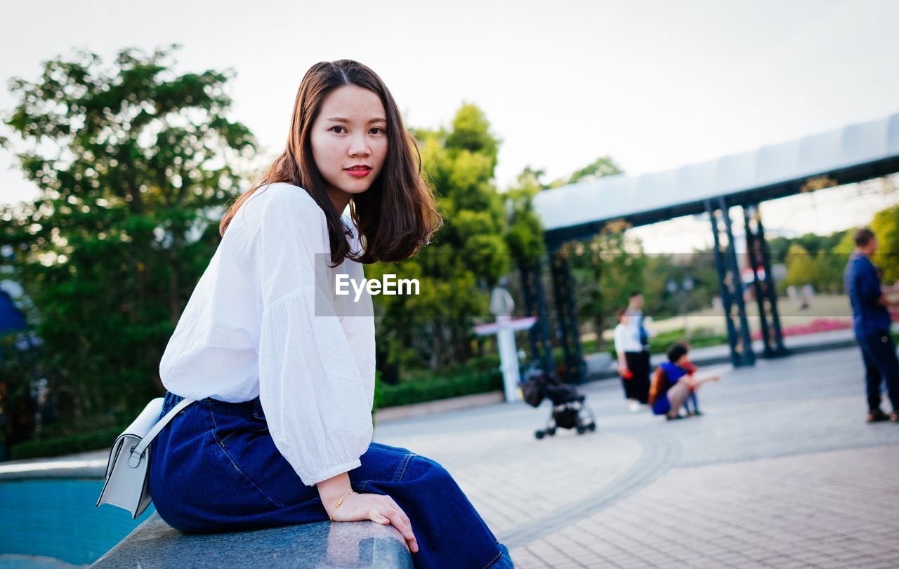 Portrait of woman sitting by fountain