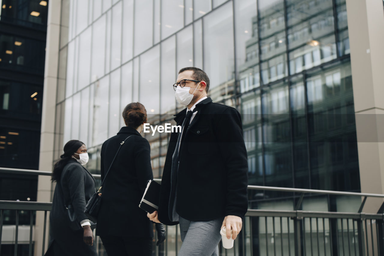 Business people walking on bridge in city during pandemic