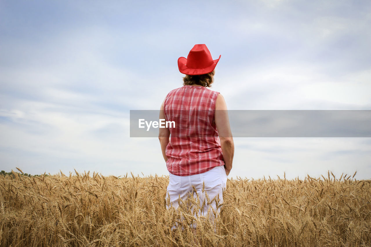 REAR VIEW OF MAN STANDING IN FIELD