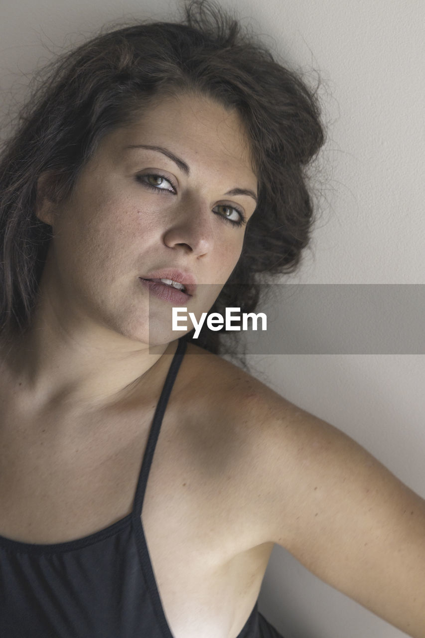 Portrait of beautiful young woman against wall