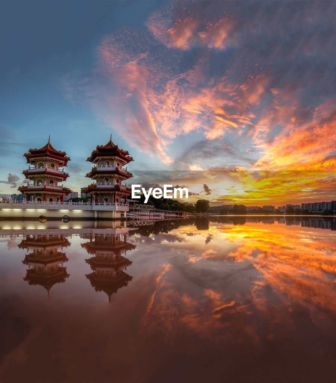 REFLECTION OF BUILDING IN LAKE AT SUNSET