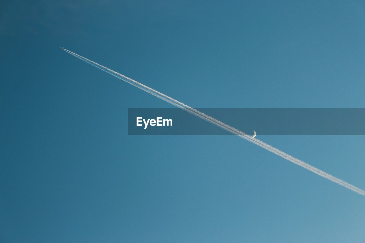 Low angle view aircraft flying against clear blue sky