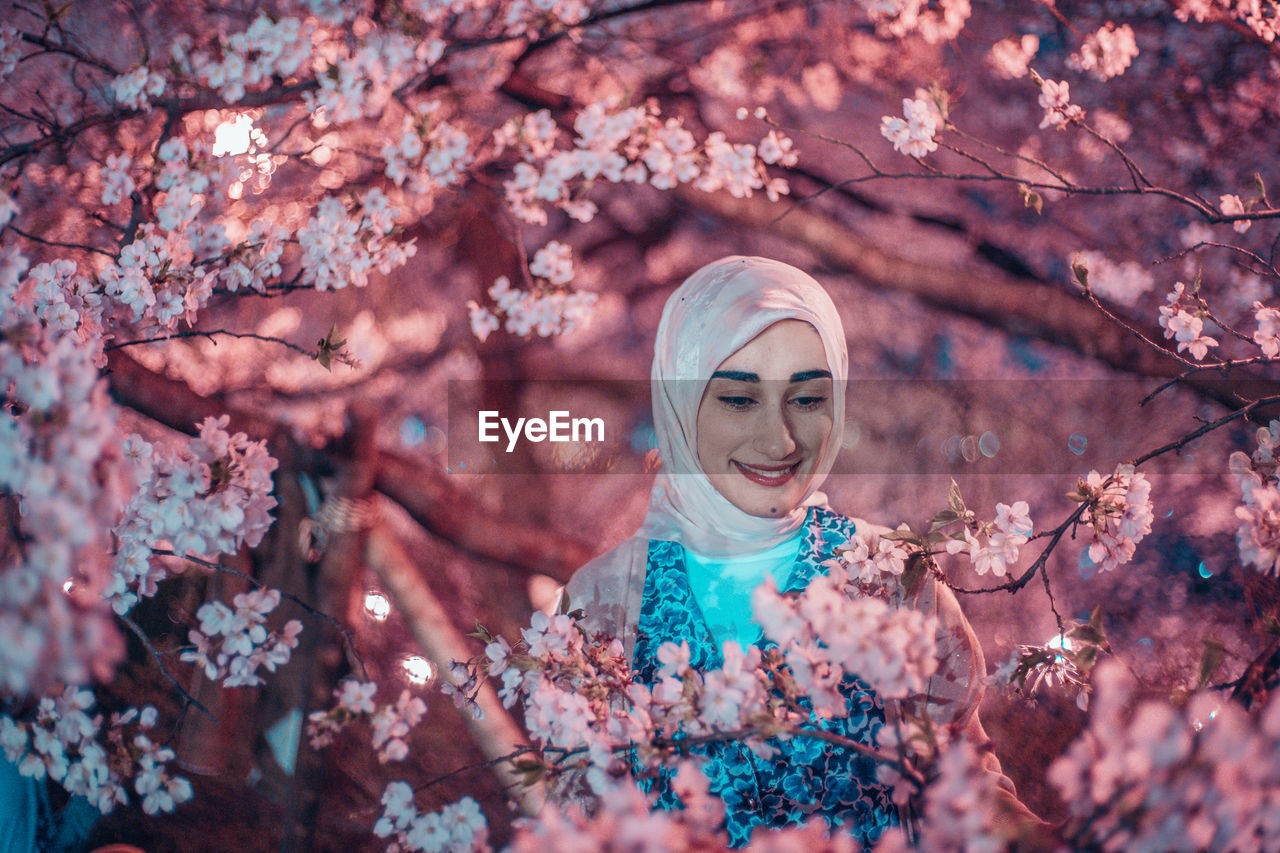 PORTRAIT OF SMILING WOMAN WITH CHERRY BLOSSOM