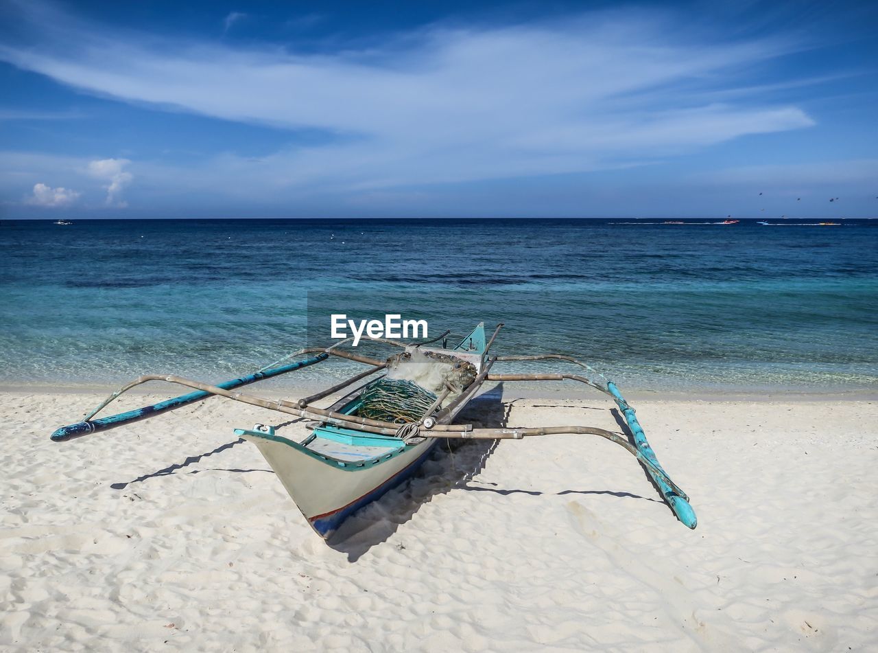 LOUNGE CHAIRS ON BEACH AGAINST SKY