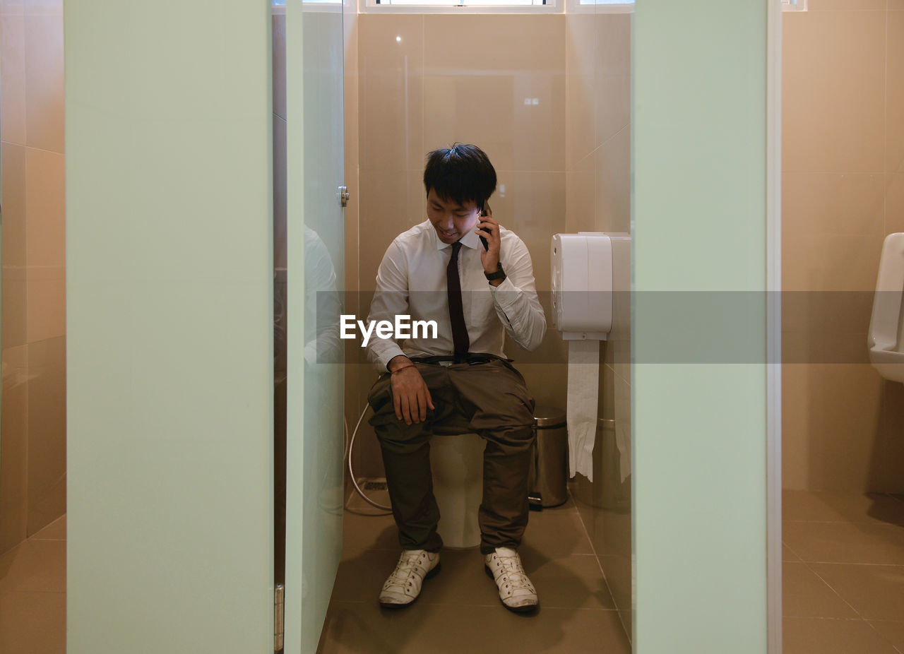 Man using mobile phone in toilet