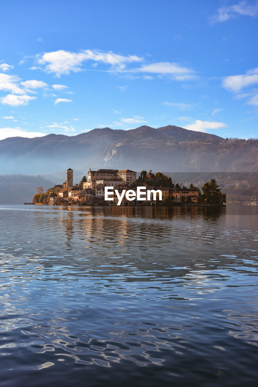 Buildings by lake orta against sky