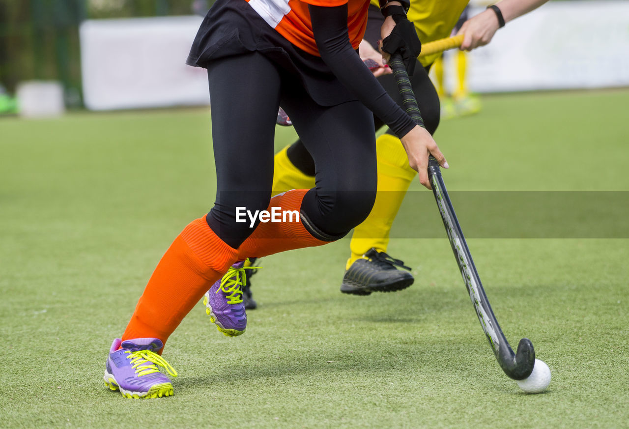 Low section of people playing hockey on field