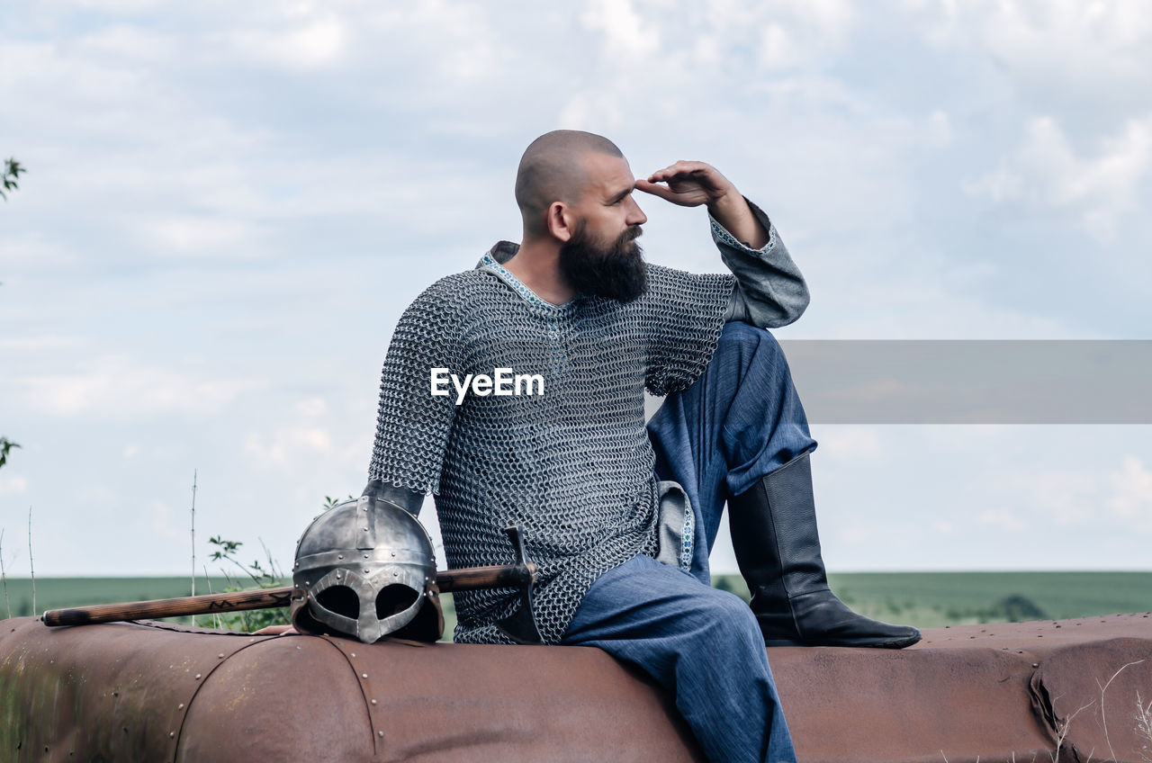 Emotional photo of medieval viking in metal chain mail, looking anxiously into the distance. 