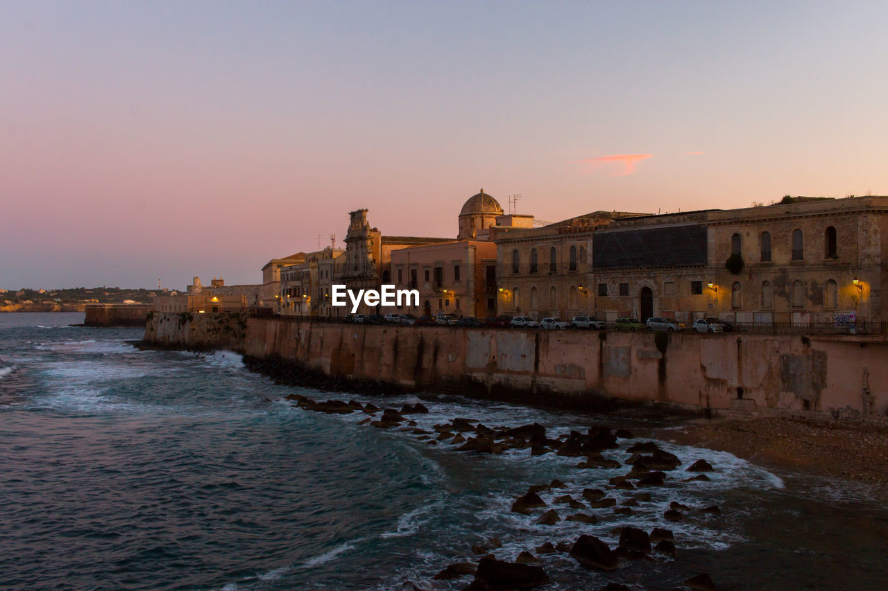 View of ortigia island by sea against sky during sunset