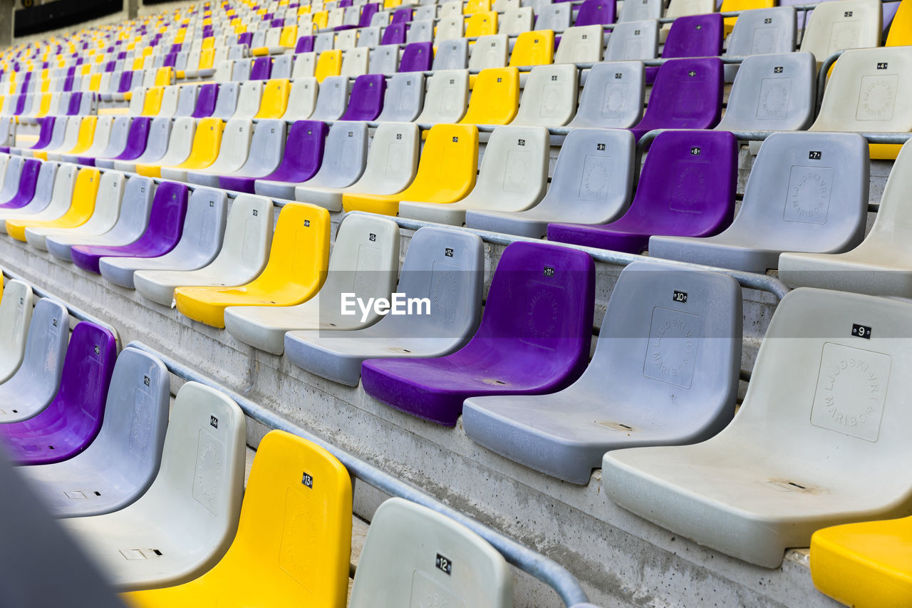 Close-up of empty multi colored chairs at stadium