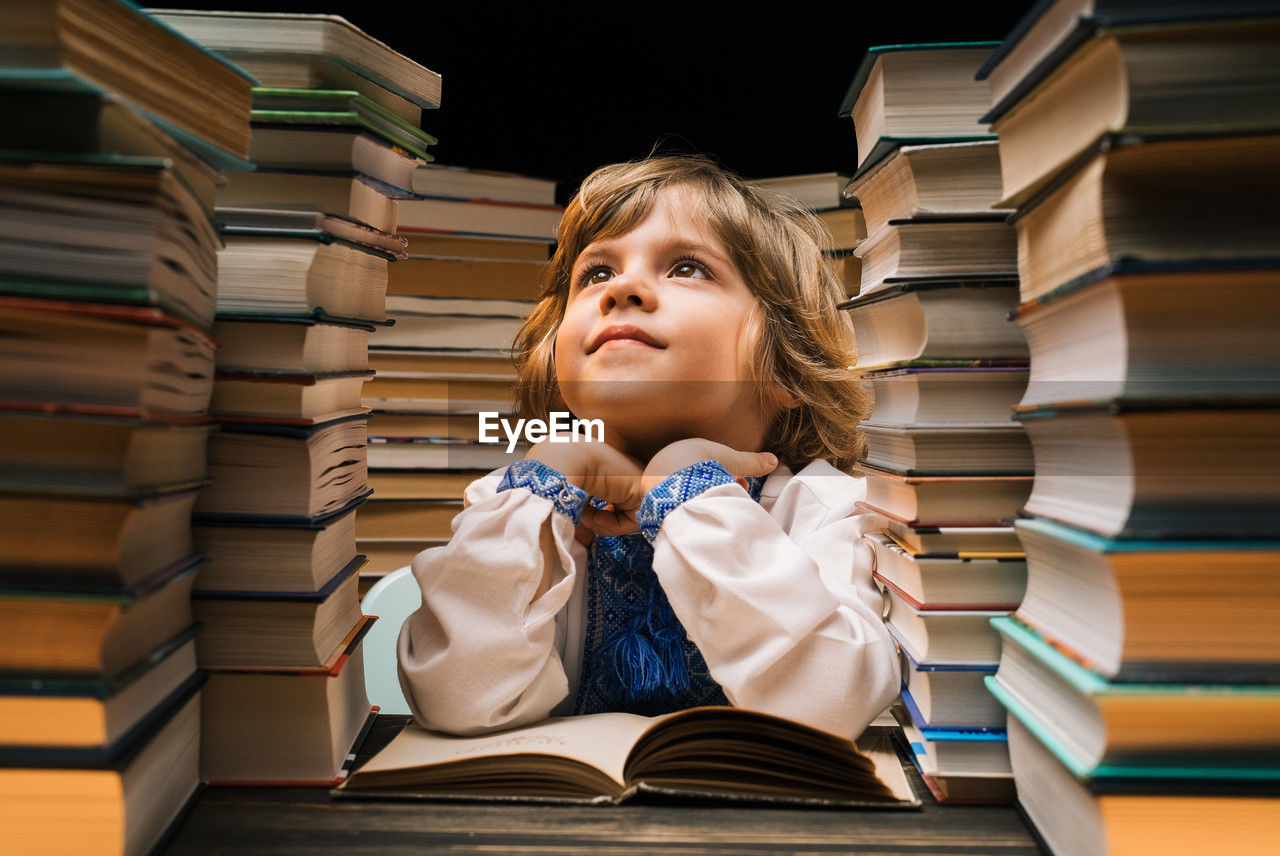 portrait of young woman sitting on books on table